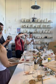 a group of people standing around a table with wine glasses and plates on top of it