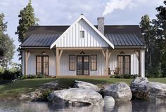 a small white house sitting on top of a lush green field next to a lake