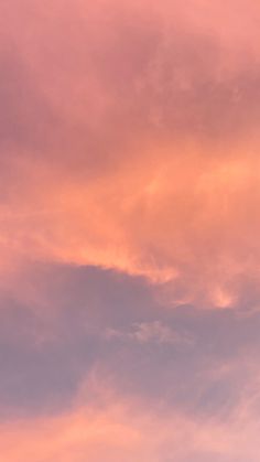 the airplane is flying high in the sky at sunset or dawn, with pink clouds behind it