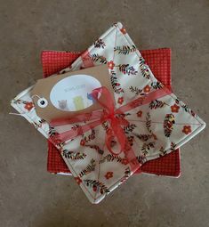 two pieces of cloth wrapped in red and white with a brown tag on top of them