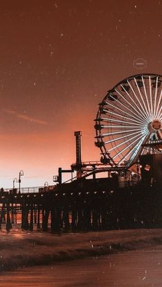 a ferris wheel sitting on top of a pier next to the ocean