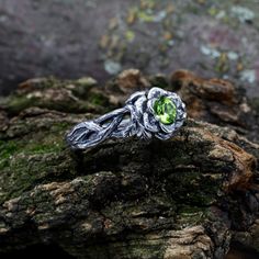 Crafted from sterling silver, our dainty branch and leaves peridot ring exudes elegance and nature-inspired charm. The intricate design features delicate leaves and a charming flower twig, creating a whimsical and unique piece. This fall-themed ring is perfect for women seeking nature-inspired jewelry.  Characteristics: Metal - Recycled solid sterling silver  Stone - Cubic Zirconia 5.0 mm Finish - Oxidized. View all silver branch rings: https://www.etsy.com/shop/TinyShinyJewel?ref=seller-platform-mcnav&section_id=43346778 Care instructions: To care for the ring, avoid contact with water and chemicals such as perfumes and lotions. When the ring is not in use, store it in a dry, cool place to prevent tarnishing. Additional information:  ✦ All rings are made to order. An average turnaround ti Flower-shaped May Birthstone Rings For Wedding, Flower Shaped May Birthstone Rings For Wedding, Flower Shaped Ring With May Birthstone For Wedding, Flower-shaped May Birthstone Wedding Rings, Nature-inspired Flower Wedding Rings, Green Sterling Silver Flower Wedding Ring, Green Sterling Silver Flower Ring For Wedding, Peridot Ring For Wedding, Green Flower-shaped Wedding Ring