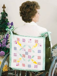 a woman sitting in a wheel chair with a quilt on it's back end