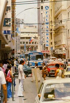 a busy city street filled with lots of traffic and people walking on the side walk