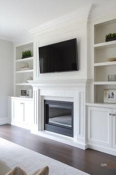 a living room with white bookcases and a flat screen tv mounted on the wall