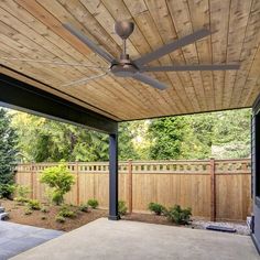 an outdoor patio with a ceiling fan and wooden fenced in area next to it