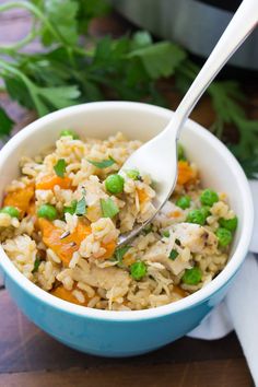 a bowl filled with rice, peas and carrots on top of a wooden table