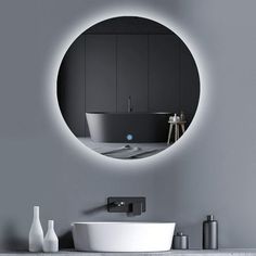 a white sink sitting under a round mirror next to a wall mounted faucet