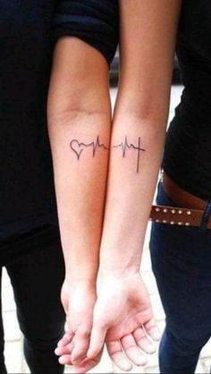 two people holding hands with tattoos on their arms and the word love written in cursive writing