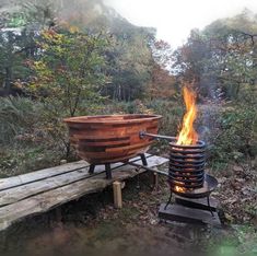 a large wooden bowl sitting on top of a fire pit next to a bench in the woods