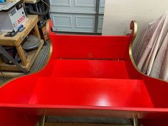 a red bench sitting in front of a garage door next to a pile of tools