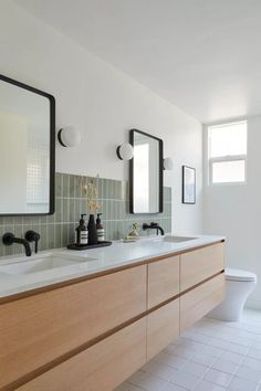 a bathroom with two sinks and three mirrors on the wall above them, along with a toilet