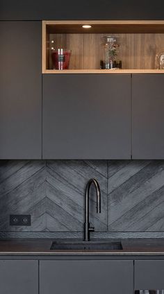 a kitchen with gray cabinets and marble counter tops, along with a stainless steel faucet