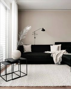 a living room with black couches and white rugs