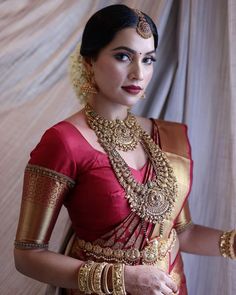 a woman in a red and gold sari with her hands on her hip, posing for the camera