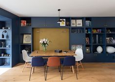 a dining room with blue walls and wooden flooring is shown in this image, there are several chairs around the table