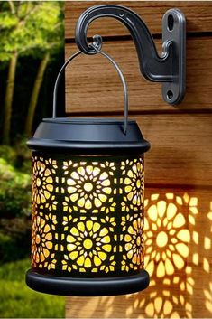 a light that is on the side of a wall next to a wooden fence and grass