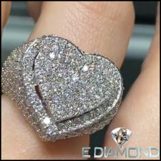 a heart shaped diamond ring sitting on top of someone's finger