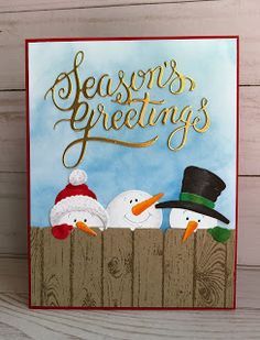 a christmas card with two snowmen in a fence and the words season's greetings written on it