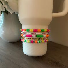 a stack of bracelets sitting on top of a table next to a white vase