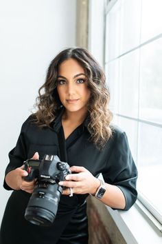 a woman holding a camera in front of a window