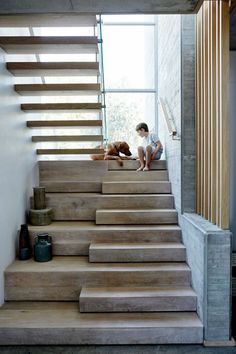 a boy and his dog are sitting on the stairs in front of a large window