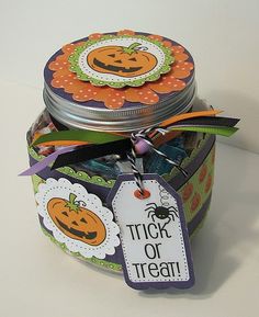 a jar filled with halloween treats on top of a white table next to a tag that says trick or treat