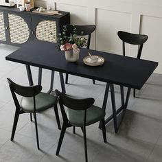 a black table with four chairs and a vase filled with flowers sitting on top of it