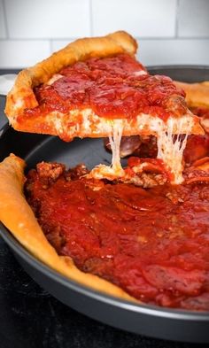 a deep dish pizza being lifted from a pan