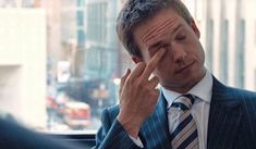 a man in a suit and tie holding his hand to his face while talking on the phone