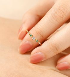 a woman's hand with a diamond and emerald ring on top of her body