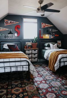 two beds in a small room with colorful rugs on the floor and ceiling fan