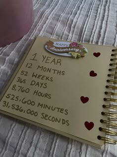 a planner with hearts on it sitting on a table next to a cup and vase