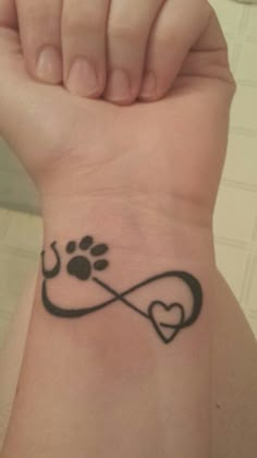 a person with a tattoo on their wrist holding a dog's paw in the shape of a heart