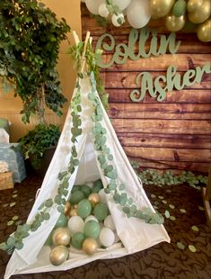 a teepee tent filled with balloons and greenery