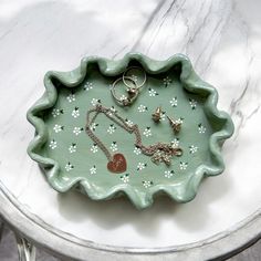 a green tray with jewelry on it sitting on top of a white marble countertop