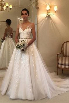 a woman standing in front of a mirror wearing a wedding dress