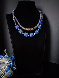 This is an ethnic style necklace made with large square dragon venis agate stones dyed blue. The necklace is double-stranded with a copper-plated brass decorative element in the center. To finish the necklace I also used agate, jade and lapiz stones. For those who love elegant retro style. All jewels are delivered in a decorated box, ready to be given as a gift to your loved one. How to take care of your jewellery: put on your beauty products (cosmetics, perfumes, ...) before wearing your precious jewel. Clean your jewelry with a soft cloth after wearing. Don't use water. Make sure you store your jewelry separately to avoid scratching it. Store away from heat sources, in a dry place in the special box. SHIPPING CONDITIONS I ship to the address you provided to us on Etsy, so be sure to chec Blue Rectangular Gemstone Necklace, Blue Square Necklace For Gifts, Blue Square Necklace For Gift, Blue Square Necklace Perfect For Gifts, Blue Agate Gemstone Beads Necklace, Bohemian Blue Rectangular Necklace, Handmade Double Strand Agate Necklace, Adjustable Blue Agate Necklaces, Adjustable Blue Agate Necklace