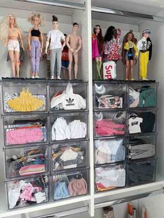 several plastic bins filled with barbie dolls and other toy items on top of shelves