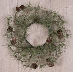 a pine cone wreath hanging on a wooden wall next to a white painted wood floor