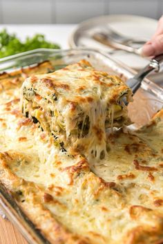 someone is taking a piece of lasagna out of the casserole dish