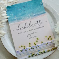 a wedding program on a plate with white flowers and palm trees in the foreground