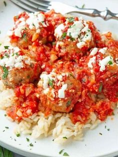 meatballs covered in marinara sauce and feta cheese on top of white rice