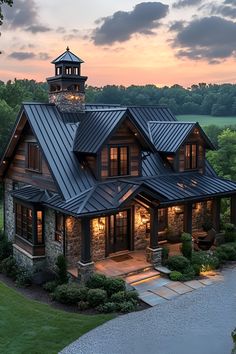 a large house with a clock tower on the top of it's roof, surrounded by lush green trees