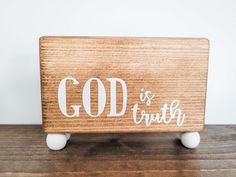 a wooden sign with the word god and truth written in white on it sitting on top of a table