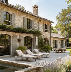 an outdoor patio with chaise lounges and water feature in front of the house