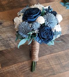 a bridal bouquet with blue and white flowers on a wooden floor in front of wood planks