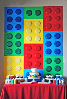 a table topped with cake and legos next to a wall made out of blocks