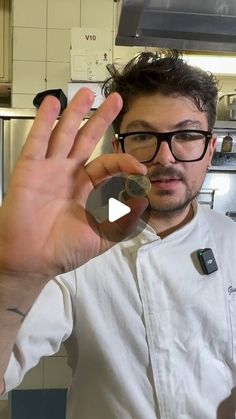 a man wearing glasses holding up a piece of metal