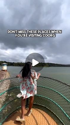 a woman standing on top of a metal fence next to the ocean with a caption that reads, don't miss these places when you're visiting corb